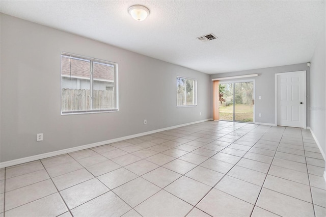 empty room with a textured ceiling and light tile patterned floors