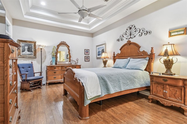 bedroom with hardwood / wood-style flooring, ceiling fan, ornamental molding, and a raised ceiling