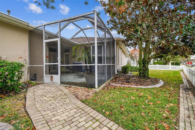 exterior space featuring ceiling fan, a yard, a patio area, and glass enclosure