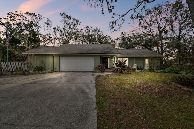 single story home featuring a garage and a lawn