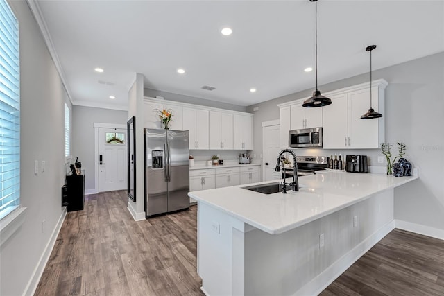 kitchen with kitchen peninsula, sink, white cabinetry, hanging light fixtures, and appliances with stainless steel finishes