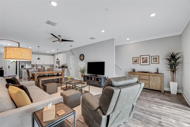 living room with ceiling fan and light hardwood / wood-style flooring