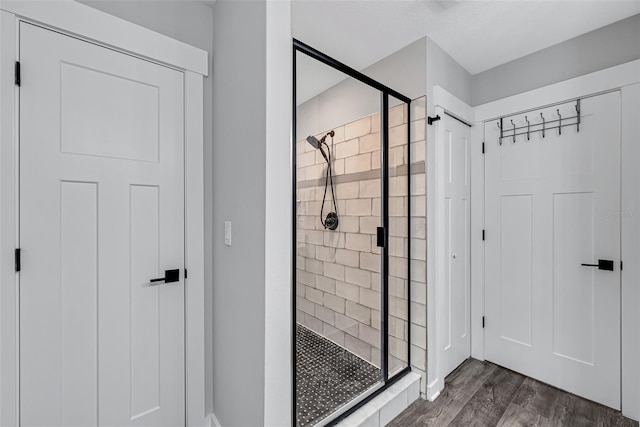 bathroom with a shower with shower door and hardwood / wood-style floors