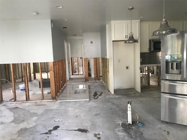 kitchen with stainless steel fridge, white cabinetry, and pendant lighting