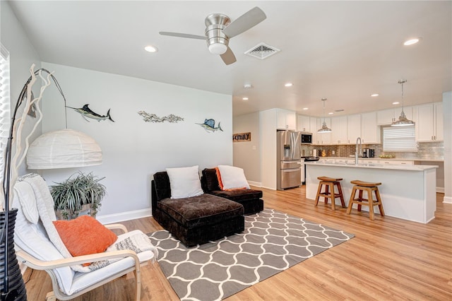 living room with light wood-type flooring and ceiling fan