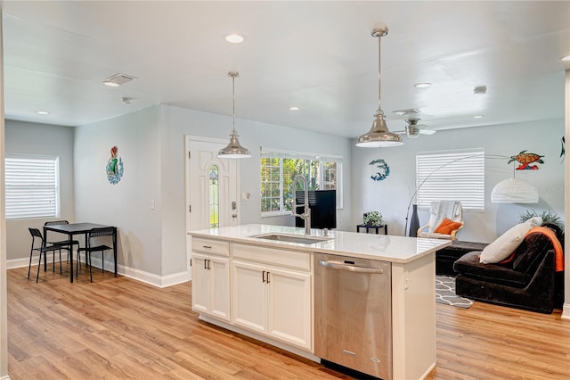 kitchen with sink, decorative light fixtures, dishwasher, light wood-type flooring, and an island with sink