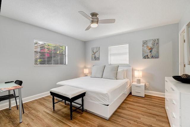 bedroom with ceiling fan, light hardwood / wood-style flooring, and a textured ceiling