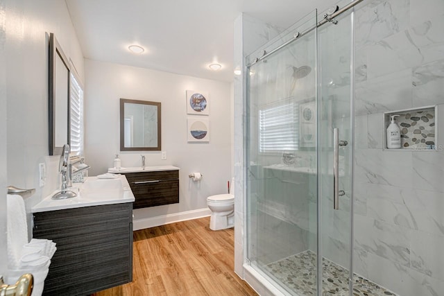 bathroom featuring a shower with door, toilet, vanity, and wood-type flooring