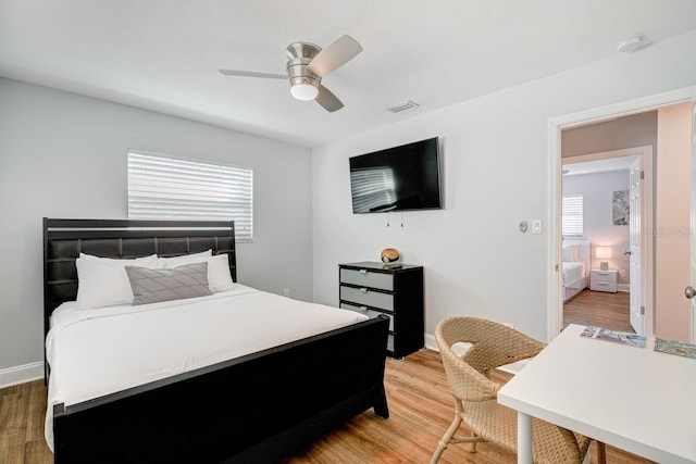 bedroom with ceiling fan, wood-type flooring, and multiple windows