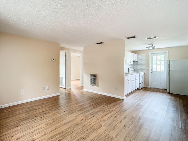 unfurnished living room with heating unit, light hardwood / wood-style flooring, and a textured ceiling