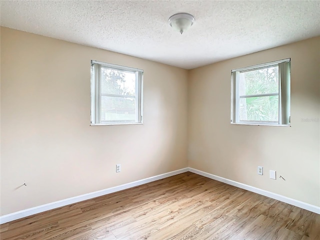 empty room with light hardwood / wood-style floors and a textured ceiling