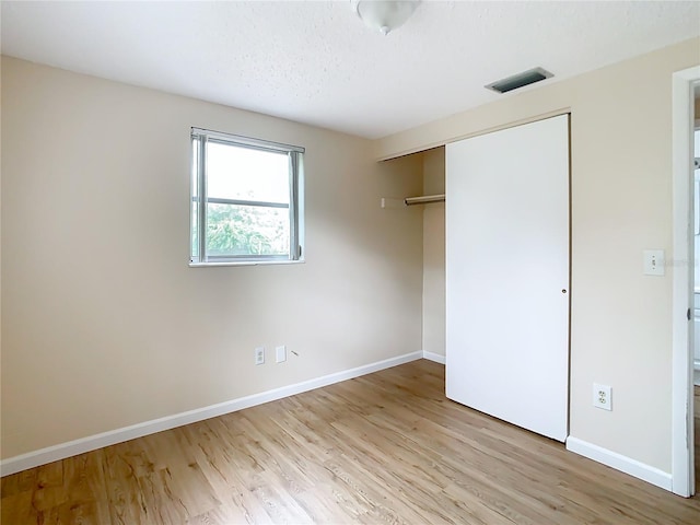 unfurnished bedroom with light wood-type flooring and a closet