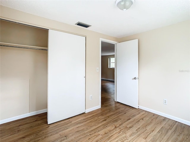 unfurnished bedroom with light hardwood / wood-style flooring and a closet