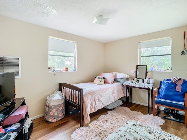 bedroom with a textured ceiling and wood-type flooring