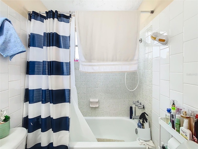 bathroom featuring toilet, tile walls, and shower / bath combo with shower curtain