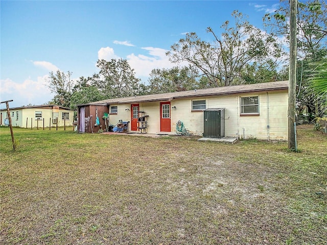 back of property featuring cooling unit and a yard