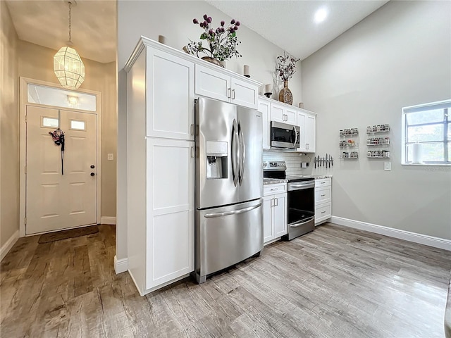 kitchen with white cabinets, backsplash, stainless steel appliances, and light hardwood / wood-style floors