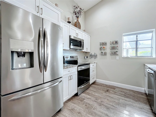 kitchen featuring light hardwood / wood-style floors, decorative backsplash, white cabinetry, light stone countertops, and appliances with stainless steel finishes