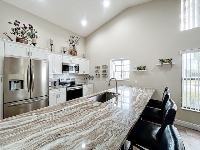 kitchen featuring white cabinets, vaulted ceiling, appliances with stainless steel finishes, and sink