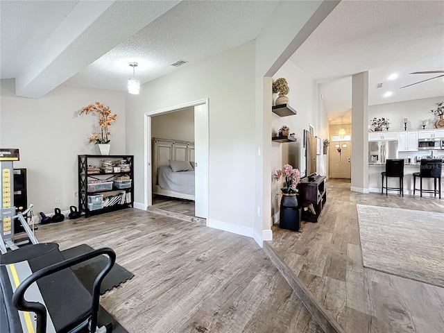 interior space featuring ceiling fan, a textured ceiling, and light wood-type flooring