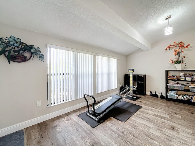 workout room featuring a textured ceiling, lofted ceiling, and light hardwood / wood-style flooring