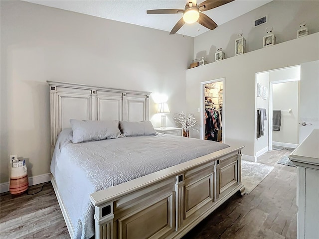 bedroom with a spacious closet, hardwood / wood-style flooring, a closet, and ceiling fan