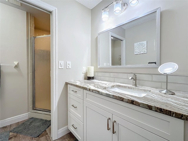 bathroom featuring vanity, decorative backsplash, and a shower with door