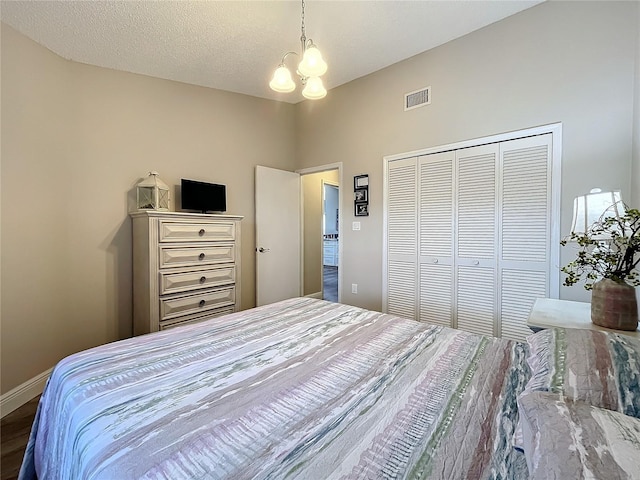 bedroom with a textured ceiling, a closet, and a chandelier