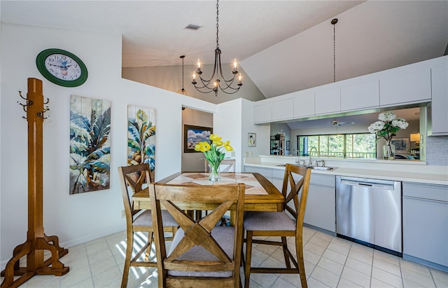 dining space with sink, light tile patterned flooring, ceiling fan with notable chandelier, and high vaulted ceiling