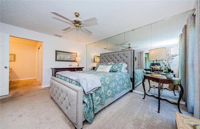 bedroom with ceiling fan, a textured ceiling, and light carpet