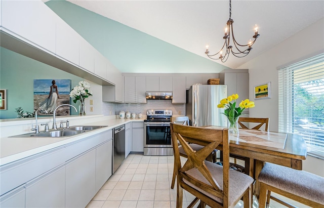 kitchen featuring appliances with stainless steel finishes, sink, backsplash, hanging light fixtures, and vaulted ceiling