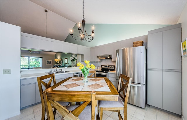 tiled dining room with high vaulted ceiling, sink, and ceiling fan with notable chandelier