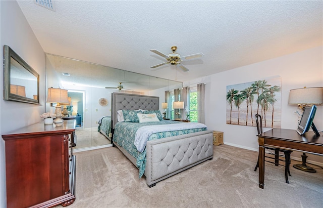 bedroom featuring light colored carpet, a textured ceiling, and ceiling fan