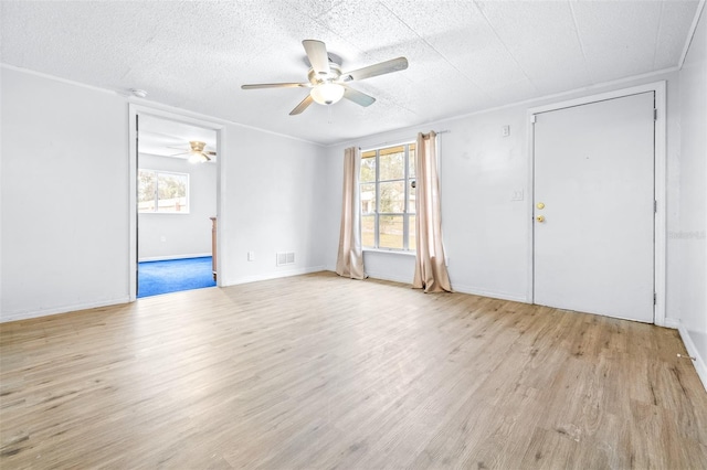 empty room with ceiling fan, light hardwood / wood-style floors, crown molding, and a wealth of natural light