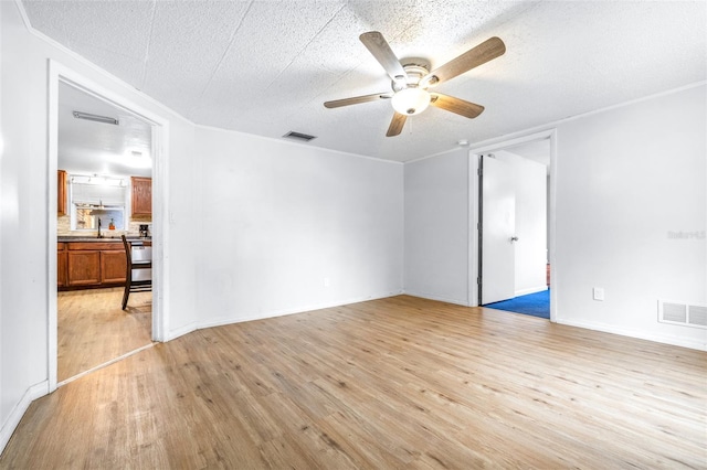 unfurnished room with sink, a textured ceiling, light wood-type flooring, and ceiling fan