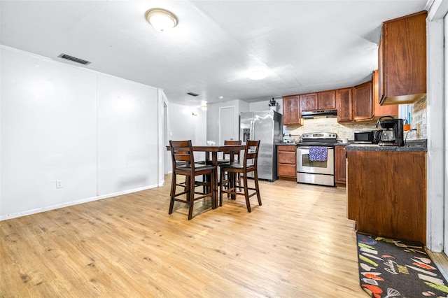 kitchen with stainless steel appliances, light hardwood / wood-style floors, and tasteful backsplash