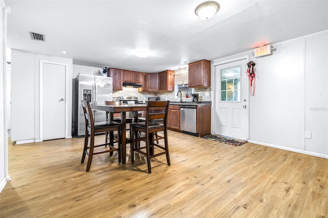 kitchen with appliances with stainless steel finishes, light hardwood / wood-style floors, tasteful backsplash, and sink