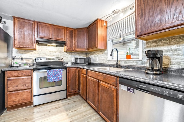 kitchen featuring stainless steel appliances, sink, tasteful backsplash, and light hardwood / wood-style flooring