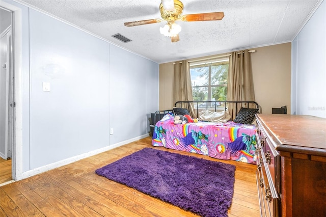 bedroom with ornamental molding, a textured ceiling, ceiling fan, and light wood-type flooring