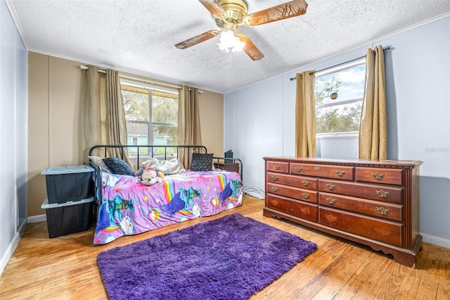 bedroom with a textured ceiling, ceiling fan, and light wood-type flooring