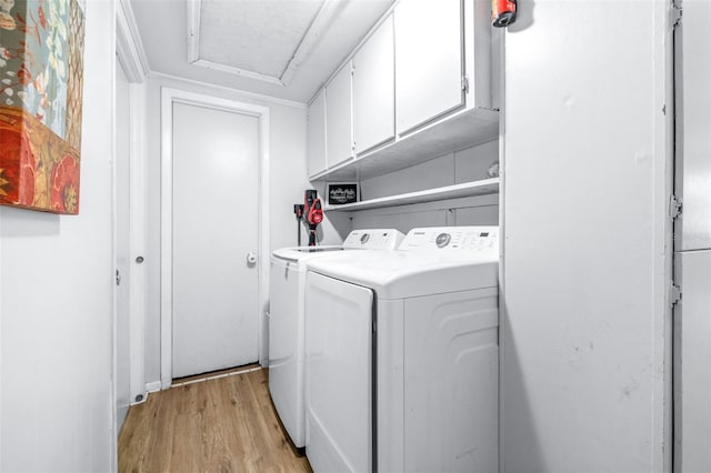 laundry area featuring washing machine and clothes dryer, light hardwood / wood-style floors, and cabinets