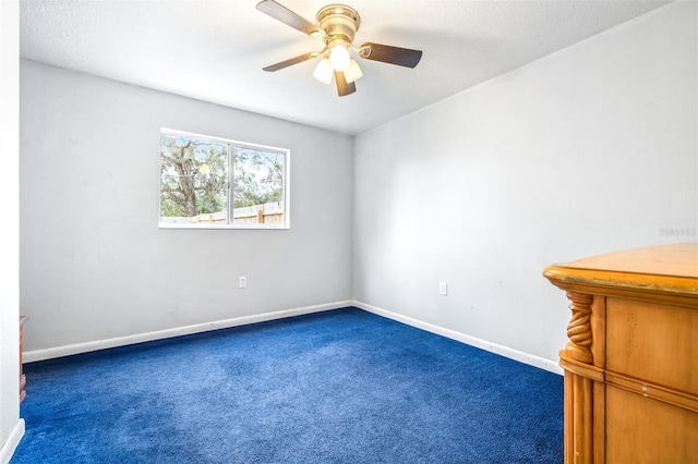 spare room featuring ceiling fan and dark carpet