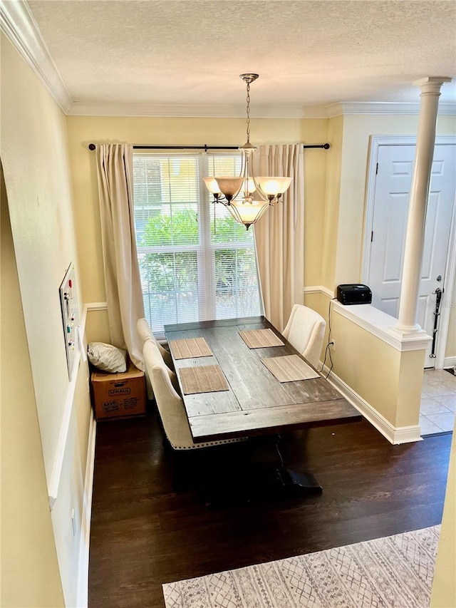 dining space featuring crown molding, an inviting chandelier, light hardwood / wood-style floors, a textured ceiling, and ornate columns