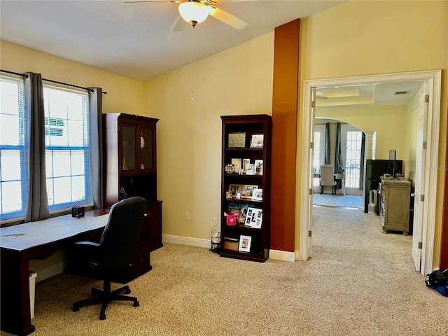 carpeted office space featuring ceiling fan, vaulted ceiling, and a textured ceiling