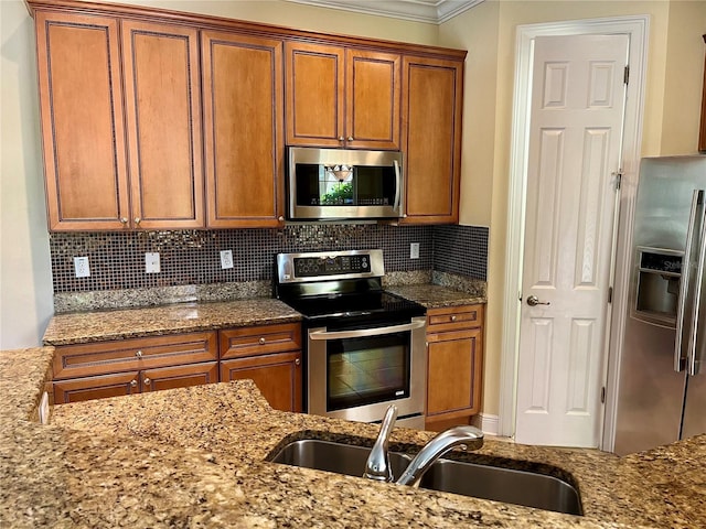 kitchen with a sink, ornamental molding, appliances with stainless steel finishes, and brown cabinets