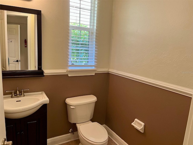 half bath with toilet, vanity, and baseboards