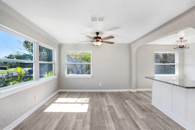 interior space with ceiling fan with notable chandelier and light hardwood / wood-style flooring