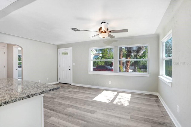 unfurnished living room with ceiling fan, a healthy amount of sunlight, and light hardwood / wood-style floors