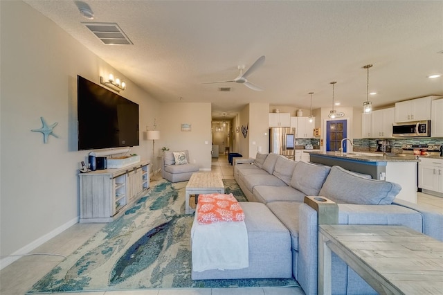 living room with ceiling fan and a textured ceiling