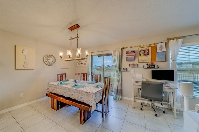 dining space with a textured ceiling, an inviting chandelier, and light tile patterned floors